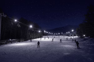 Night skiing at Karakol Resort with floodlights illuminating the slopes under a dark sky